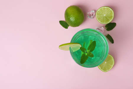 Glass of lime cocktail and ingredients on pink backgroundの写真素材