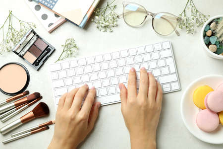 Female hands typing on keyboard on background with woman accessories