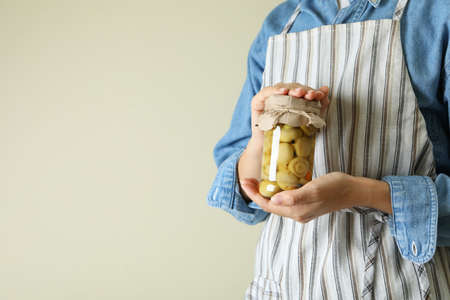 Woman holds glass jar of marinated mushroomsの写真素材
