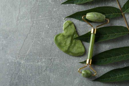 Face roller, gua sha and twig on gray textured backgroundの写真素材