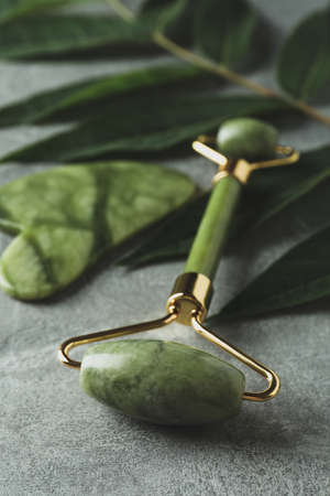 Face roller, gua sha and twig on gray textured backgroundの写真素材