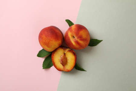 Ripe peach fruits with leaves on two tone backgroundの写真素材