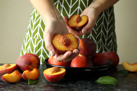 Girl in green apron holds ripe peach fruitsの写真素材