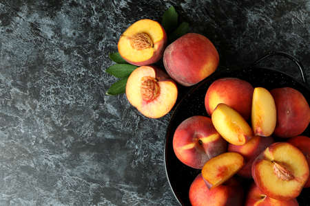Bowl with peach fruits on black smokey tableの写真素材