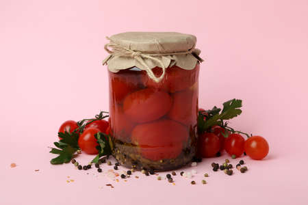 Jar with pickled tomatoes and ingredients on pink backgroundの写真素材