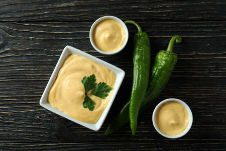 Bowls with cheese sauce and pepper on wooden tableの写真素材