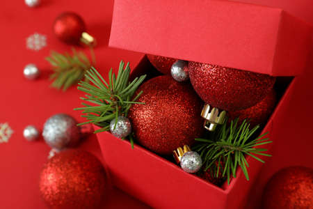Gift box and Christmas baubles on red backgroundの写真素材