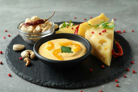 Tray with cheese sauce and ingredients on gray textured tableの写真素材