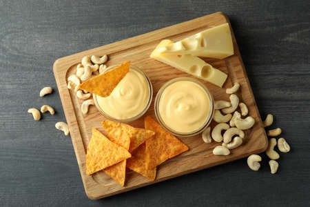 Concept of snack with cheese sauce on dark wooden table, top view