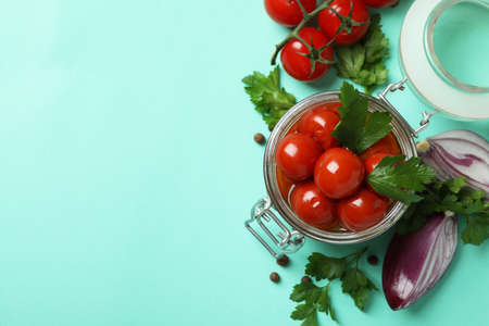 Jar with pickled tomatoes and ingredients on mint backgroundの写真素材