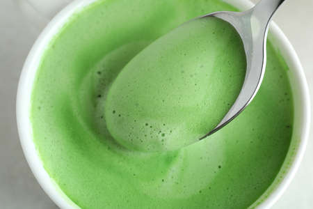 Cup and spoon with matcha latte, close up