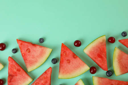 Flat lay with watermelon slices and berries on mint backgroundの写真素材