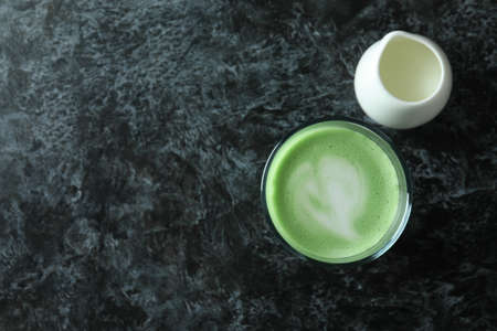 Glass of matcha latte and milk on black smokey backgroundの写真素材