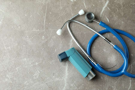 Asthma inhaler and stethoscope on gray textured tableの写真素材