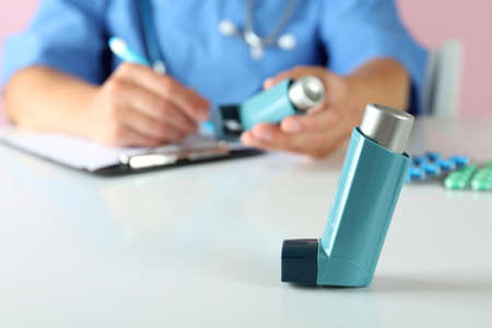 Inhaler against nurse sitting at the table and writingの写真素材
