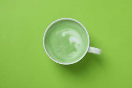 Cup of matcha latte on green backgroundの写真素材