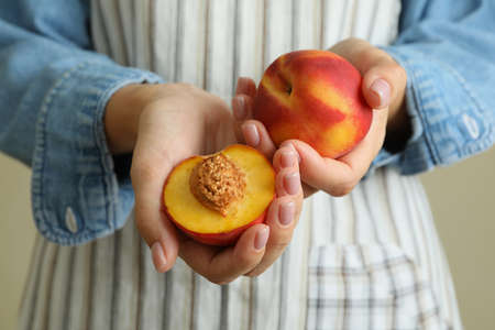 Girl in apron holds ripe peach fruitsの写真素材