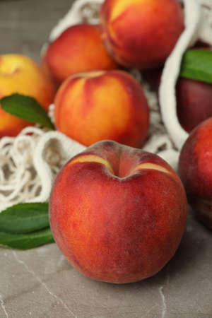 String bag with peach fruits on gray textured tableの写真素材