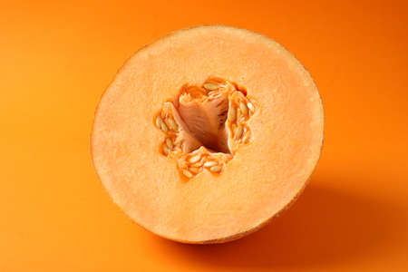 Ripe melon on orange background, close up
