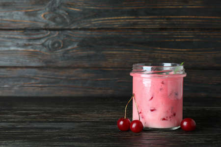 Glass jar of cherry smoothie and ingredients on rustic wooden tableの写真素材