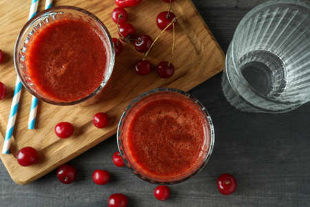 Glasses of cherry smoothie and ingredients on dark textured tableの写真素材