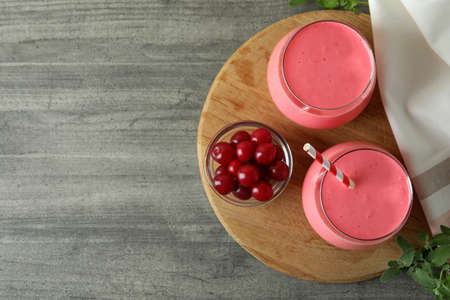Glasses of cherry smoothie and ingredients on gray textured tableの写真素材