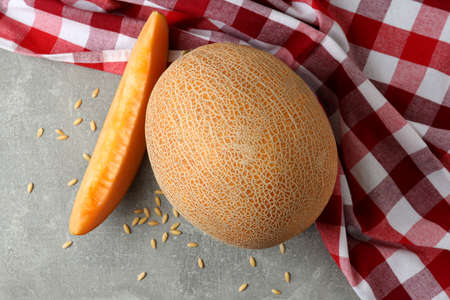 Ripe melon on gray textured table with kitchen towelの写真素材