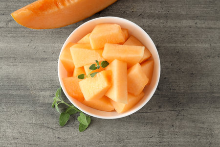Bowl with melon pieces on gray textured tableの写真素材
