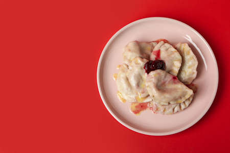 Plate with pierogi with cherry on red backgroundの写真素材