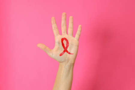 Female hand with breast cancer awareness sign on pink backgroundの写真素材