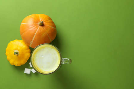 Glass of pumpkin latte and ingredients on green backgroundの写真素材