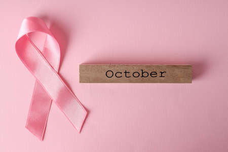 Breast cancer awareness ribbon and wooden block with text October on pink backgroundの写真素材