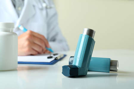 Inhaler against female doctor sitting at the table and writingの写真素材
