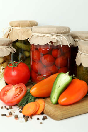 Jars of pickled vegetables and ingredients on white tableの写真素材