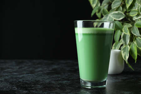 Glass of matcha latte on black smokey table