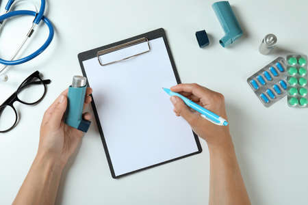 Female hands hold inhaler and writing, top viewの写真素材