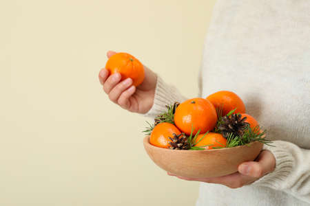 Woman in sweater holds bowl with mandarins, space for textの写真素材