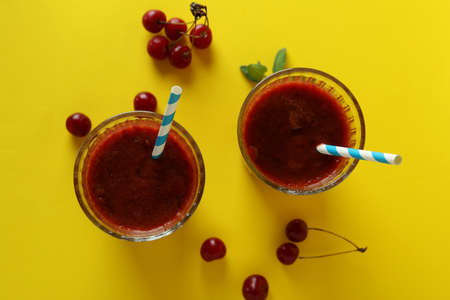 Glasses of cherry smoothie and ingredients on yellow backgroundの写真素材