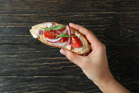Female hand holds bruschetta on rustic wooden backgroundの写真素材