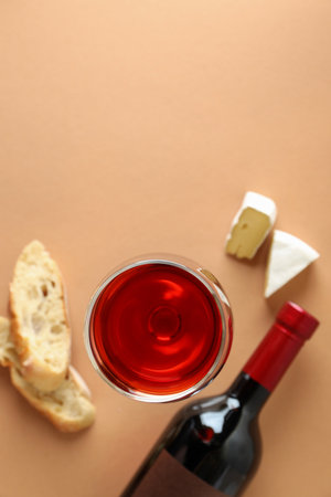 Bottle and glass of wine, cheese and bread on beige backgroundの写真素材