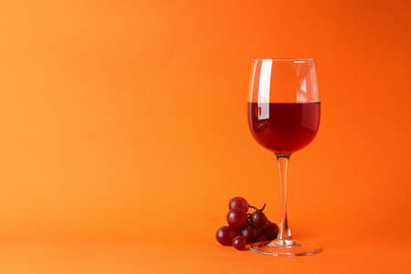Glasses of red wine and grape on orange backgroundの写真素材