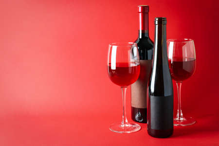 Bottles and glasses of wine on red backgroundの写真素材