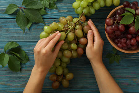 Female hands hold grape on wooden background