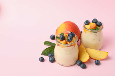 Concept of healthy food with peach yogurt on pink background
