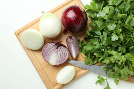 Board with onion, parsley and knife on white backgroundの写真素材