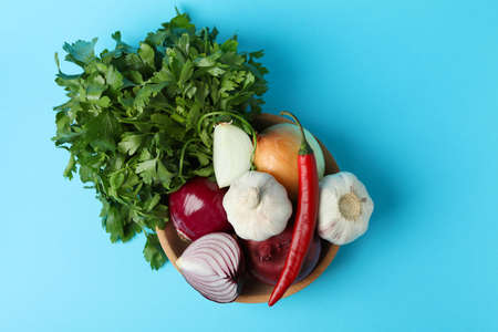 Bowl with spicy vegetables and parsley on blue backgroundの写真素材