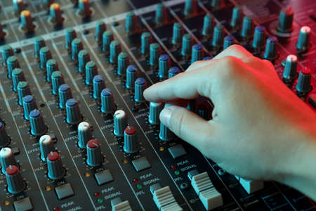 The musician adjusts the sound on audio mixer