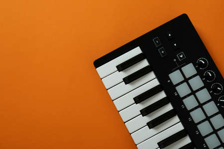 Midi keyboard on orange background, space for text
