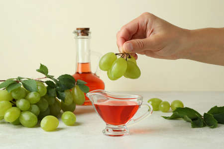 Female hand holds grape over the sauce boat with vinegarの写真素材