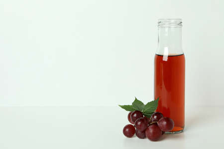 Bottle of vinegar and grape on white tableの写真素材